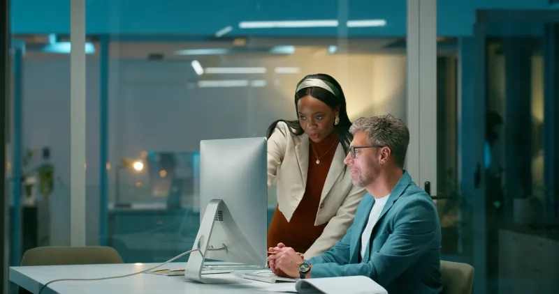 man and woman in front of computer at the office
