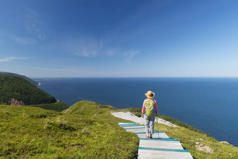 Woman walking on boardwalk at the top of Skyline Trail in Cape Breton Highlands National Park, Cabot Trail in Nova Scotia, Canada.