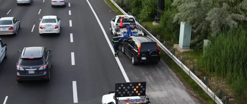 Tow truck driver on the side of the road.