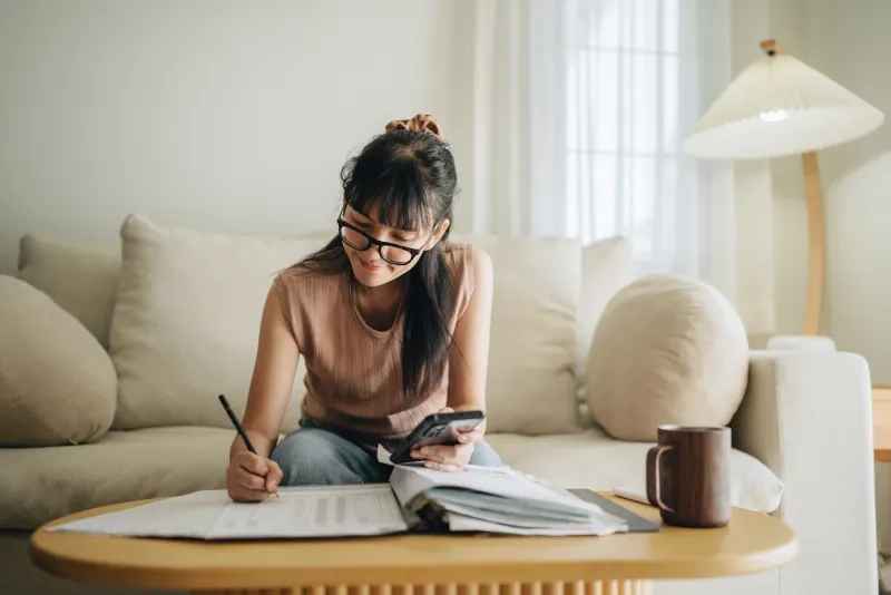 woman planning budget and using calculator on smartphone