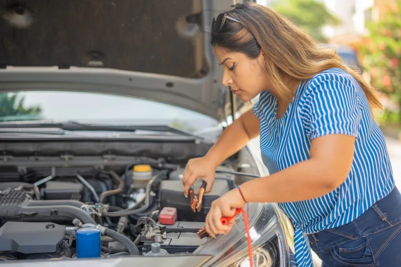 Woman trying to fix her car battery