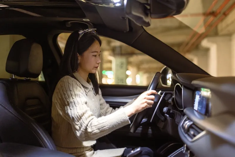 Young woman concentrates on driving while navigating through an urban parking garage.
