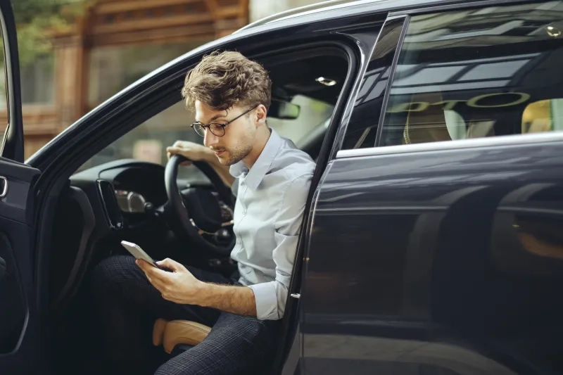 Man leaving car looking at his phone