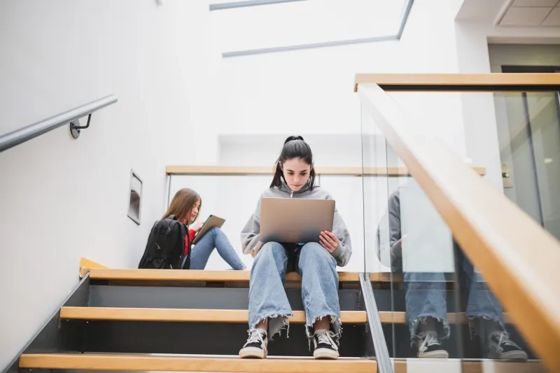 university student working on laptop on stairs