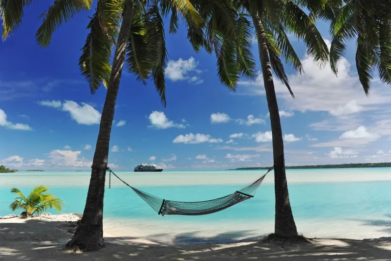 cruise ship appears on the horizon of a tropical turquoise lagoon
