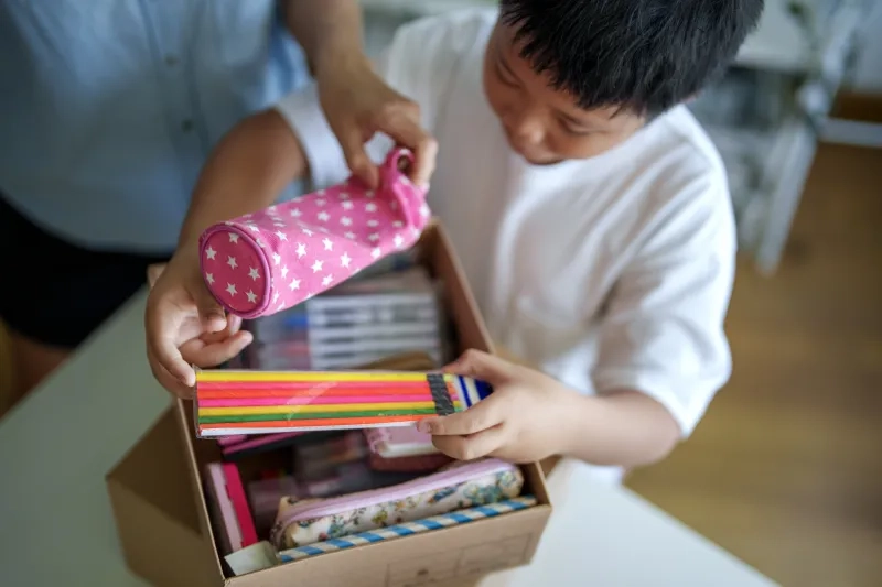 A mother and her young son sorting and packing school supplie