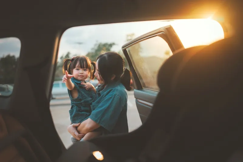 Mother holding baby daughter after exiting car