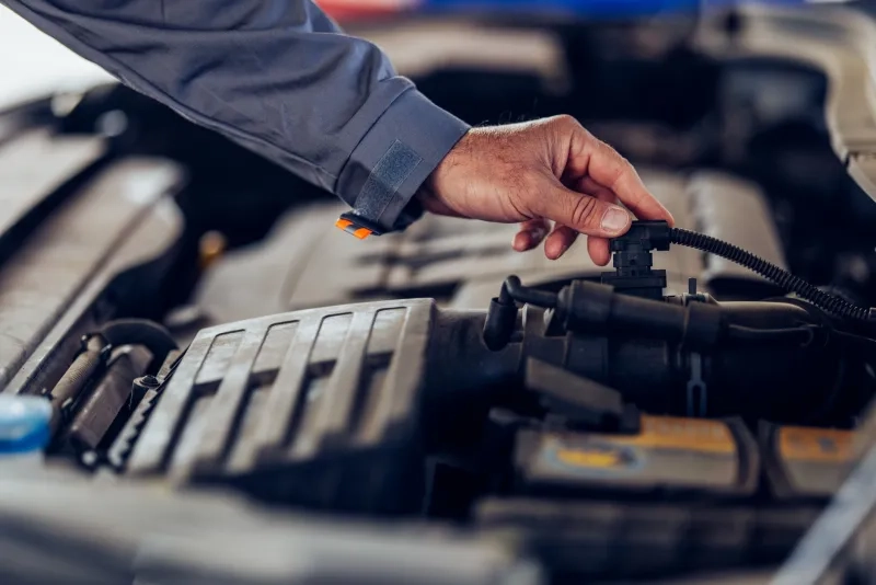 Close-up of a mechanic's hand inspecting a car engine,