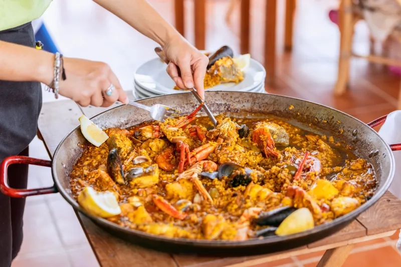 erving of traditional spanish seafood paella from the fry pan with mussels, langoustine and fish stock