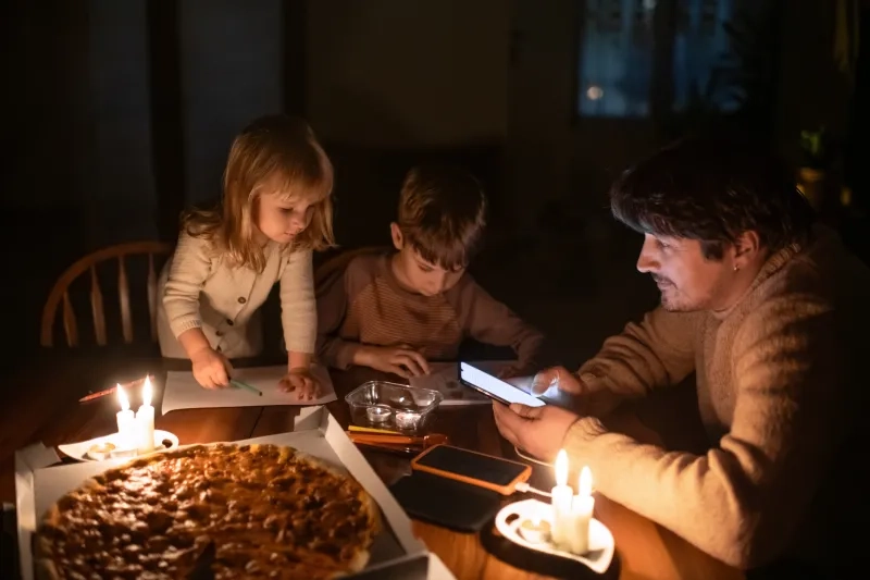 Family sitting at home with candles and eating pizza during blackout