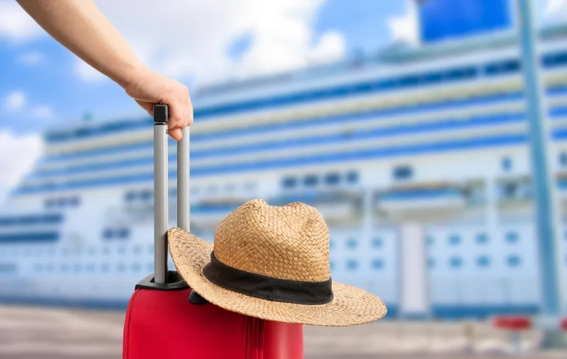 a red suitcase near a cruise ship