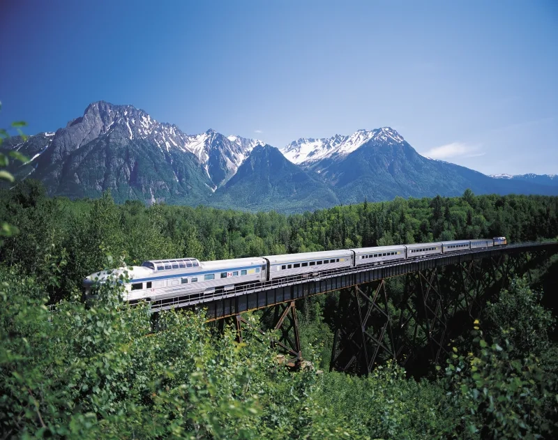 A passenger train crossing a bridge in the mountains