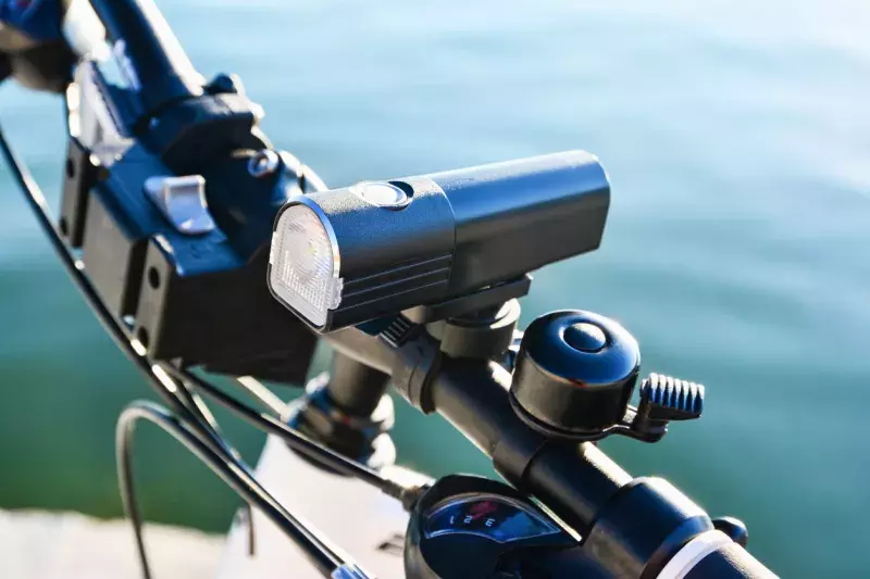 Close-up of bicycle front light and bell on a handlebar