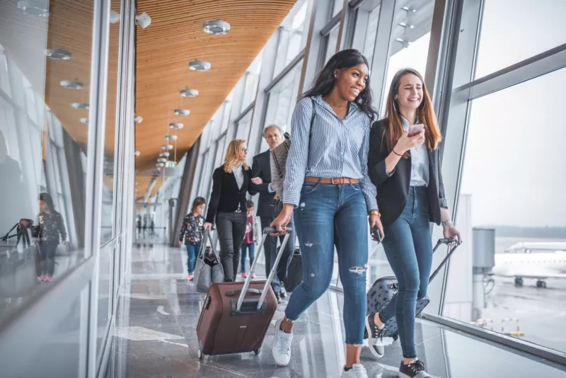 Female friends walking by window at airport