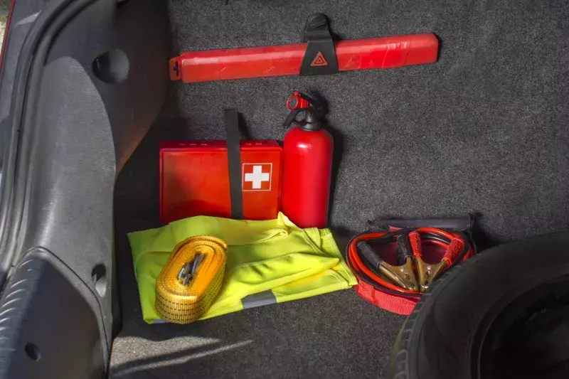 Interior of the trunk of the car in which there is a first aid kit, fire extinguisher, warning triangle, reflective vest, starter cables and tow rope