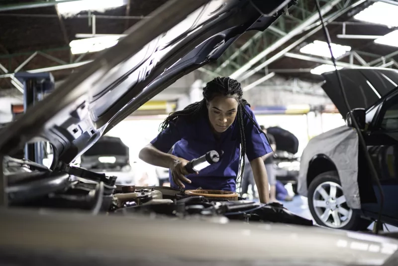 Woman repairing a car in auto repair shop