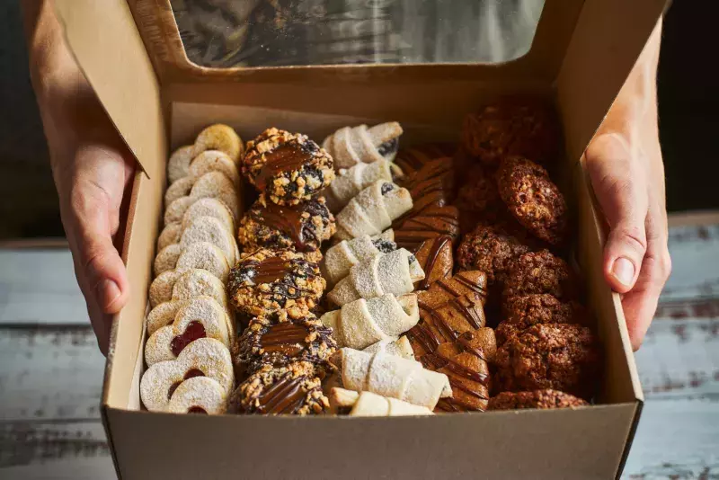 Woman holding a box filled with mini Christmas pastry cakes