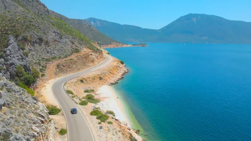 Grey car driving along the beautiful shoreline of a scenic remote island