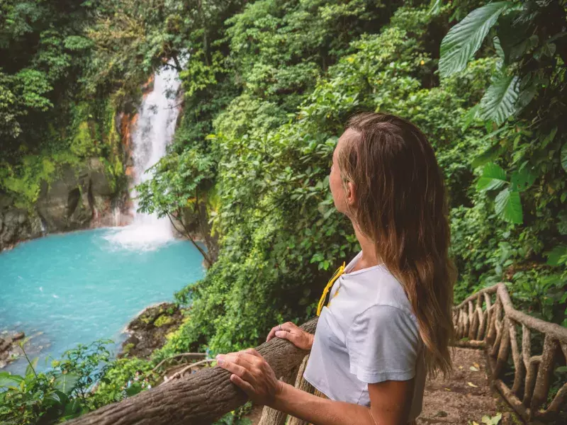 Young woman contemplating turquoise waterfall in Costa Rica