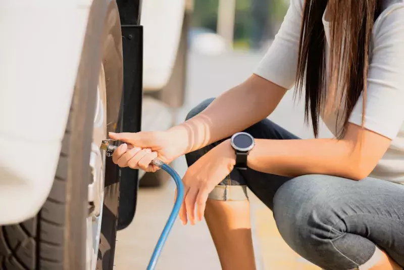 Woman driver checking air pressure and filling air in the tires close up.