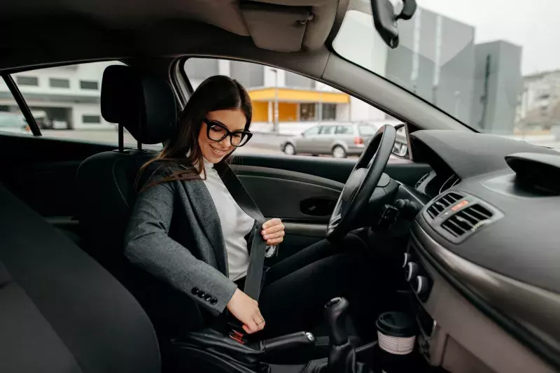 woman sitting in a car putting on her seat belt