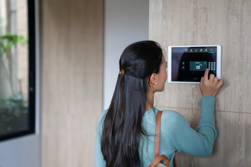 Woman entering pin to lock the door of her house using a home automation system