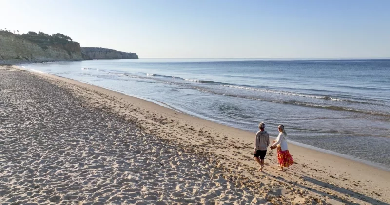 Aerial view of mature couple walking down sandy beach