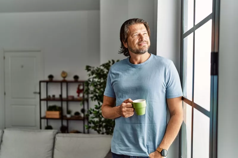 Middle age man smiling confident drinking coffee at home