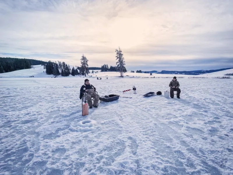 Indigenous and Caucasian Senior Men Friends Ice Fishing on Lake