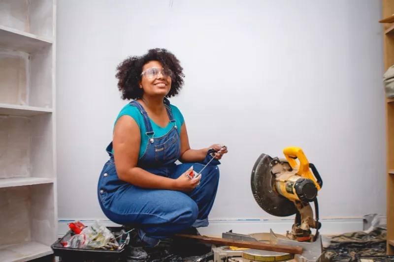 woman working on home renovations, cutting piece of wood