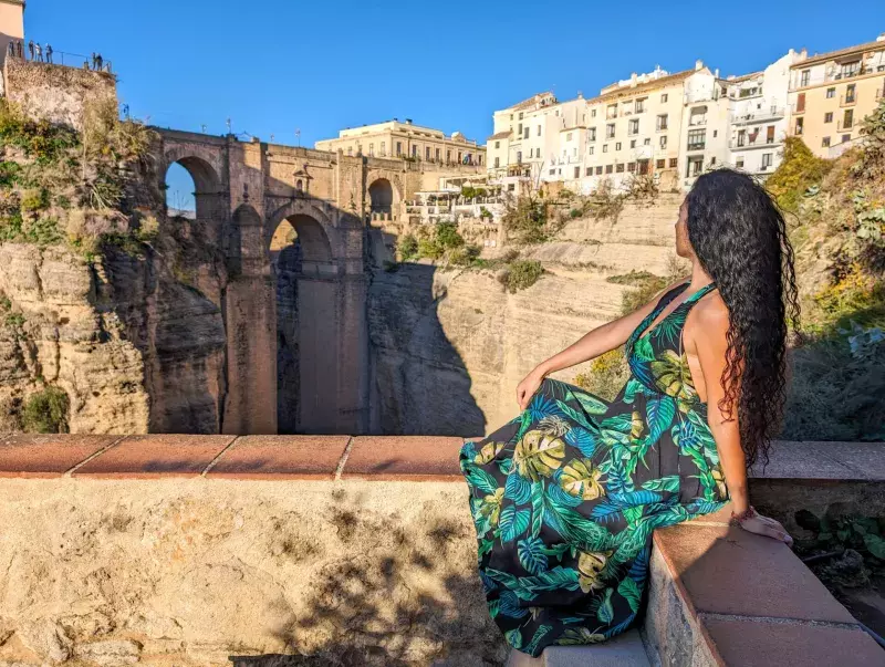 Woman tourist visiting Ronda in Andalusia, Spain. She is watchingn the famous Puente Nuevo bridge in Ronda in the morning.