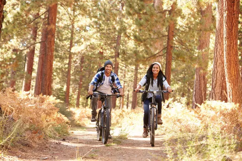 Couple Cycling Through Fall Woodland