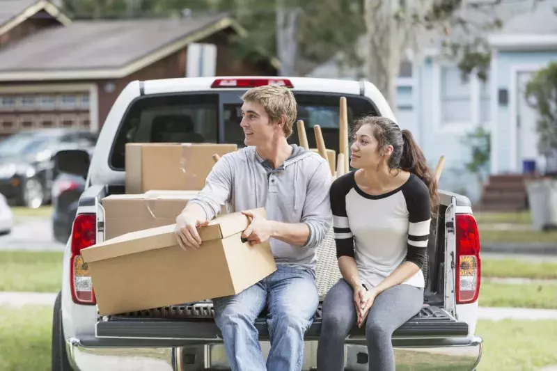 Young couple moving into new home, on pickup truck