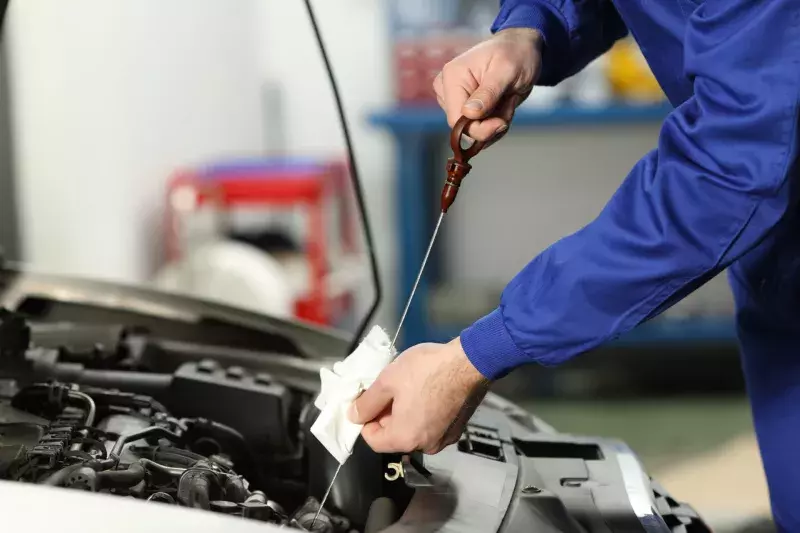 Car mechanic checking oil level