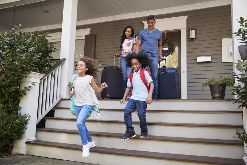 Family With Luggage Leaving House For Vacation