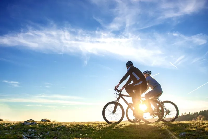 Happy mountain bike couple outdoors have fun together on a summer afternoon sunset